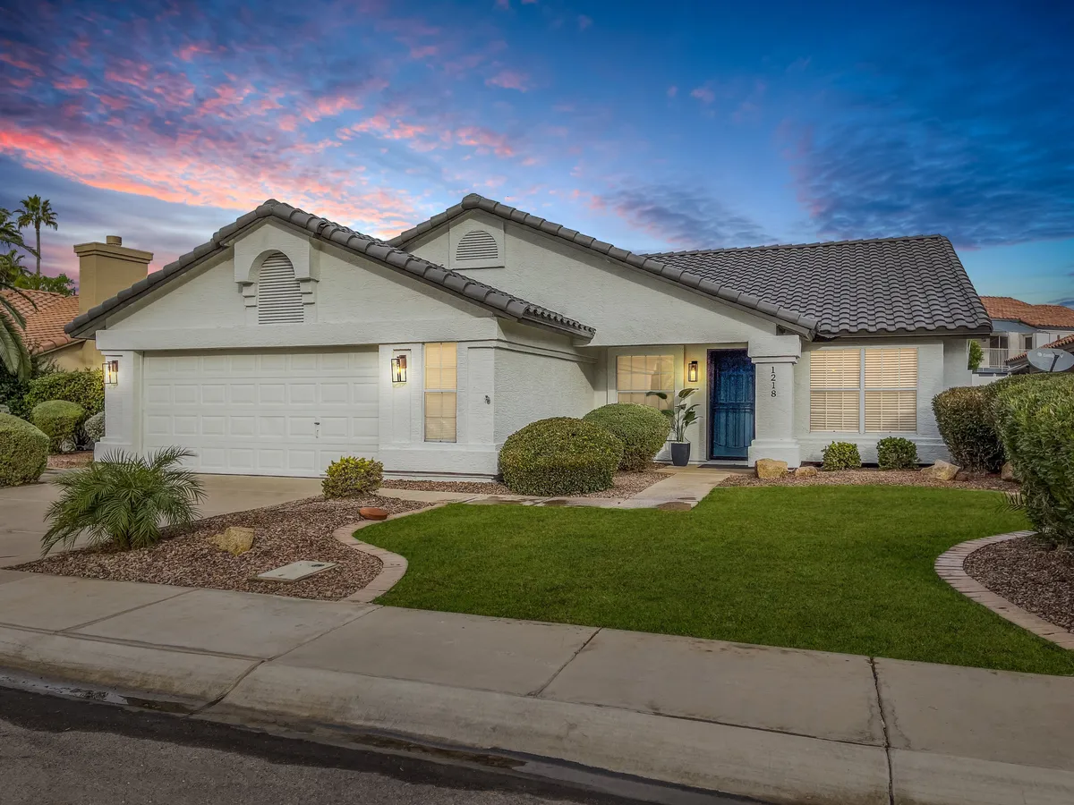 A well-manicured front lawn leads to a blue-doored entrance, framed by decorative shrubs. The inviting scene suggests a welcoming environment for friends and family to gather, relax, or enjoy outdoor activities together in a serene setting.