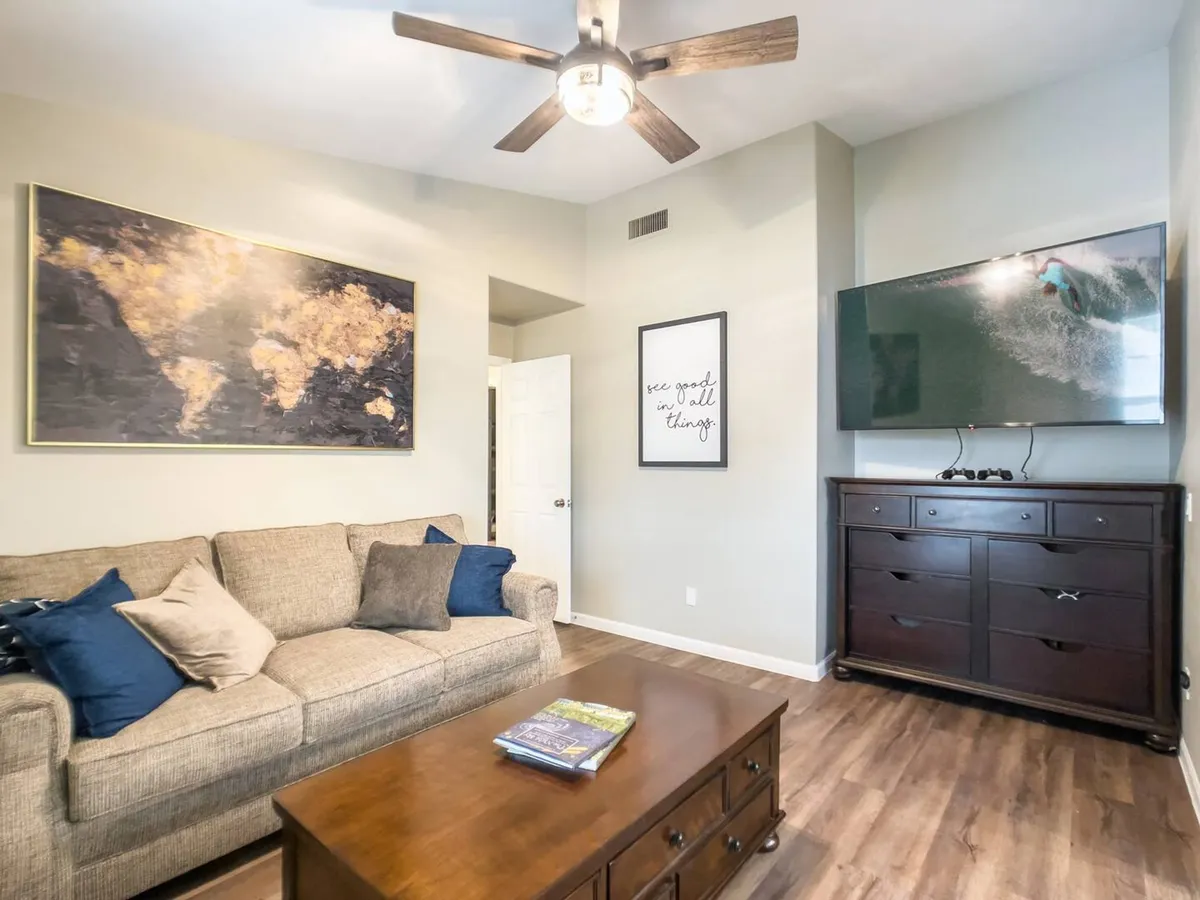 A welcoming living room with a plush sofa, coffee table, large wall-mounted TV, and world map artwork. The arrangement encourages conversation and relaxation, making it ideal for socializing or spending quiet evenings in comfort.