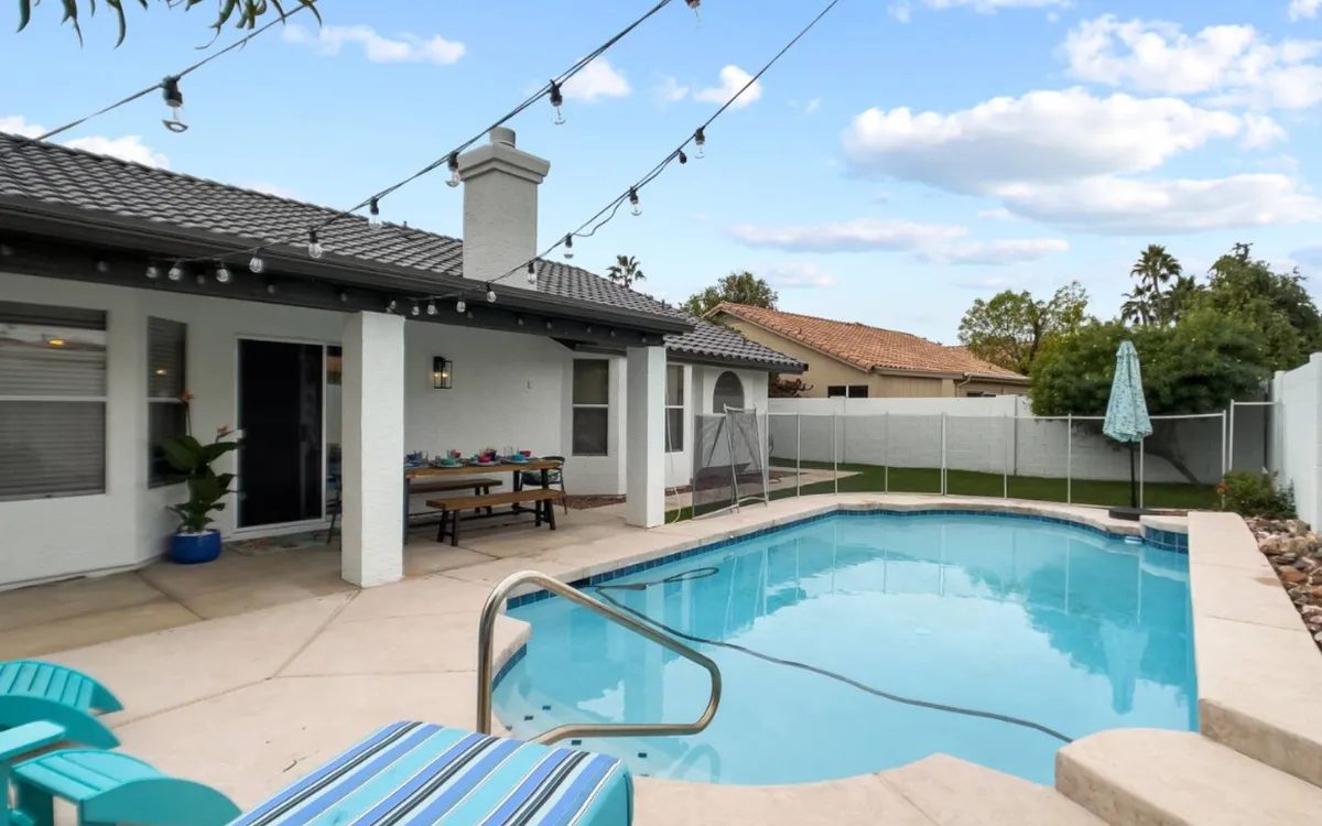 An inviting outdoor area featuring a swimming pool, outdoor seating, string lights, and a dining table. The scene evokes the ambiance of festive group dinners or relaxed after-work conversations under the stars, making it ideal for social connections and team bonding.