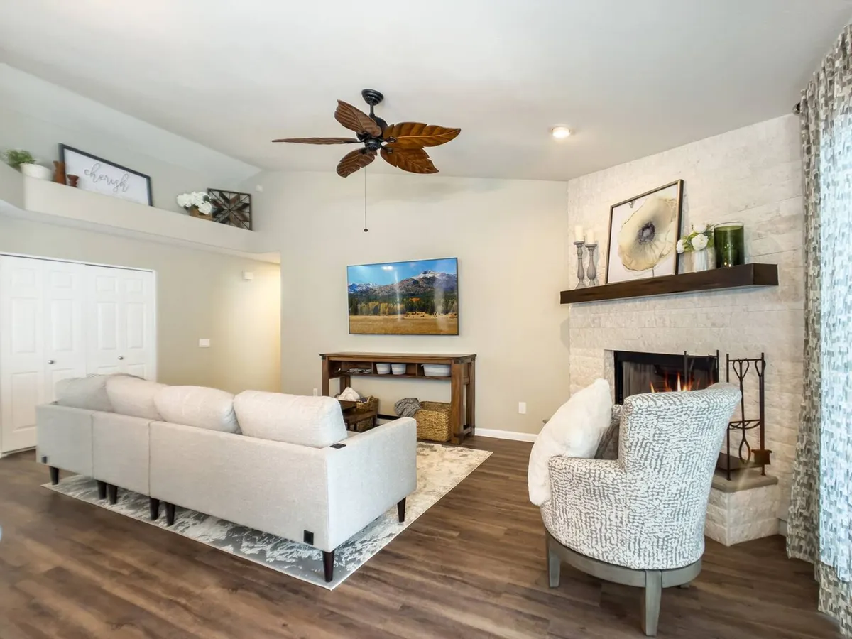 A comfortable living space with a soft sofa, decorative shelf, fireplace, and a flat-screen television. The room is styled for relaxation, with window treatments and thoughtful decor providing a cozy ambiance ideal for unwinding after a full day.