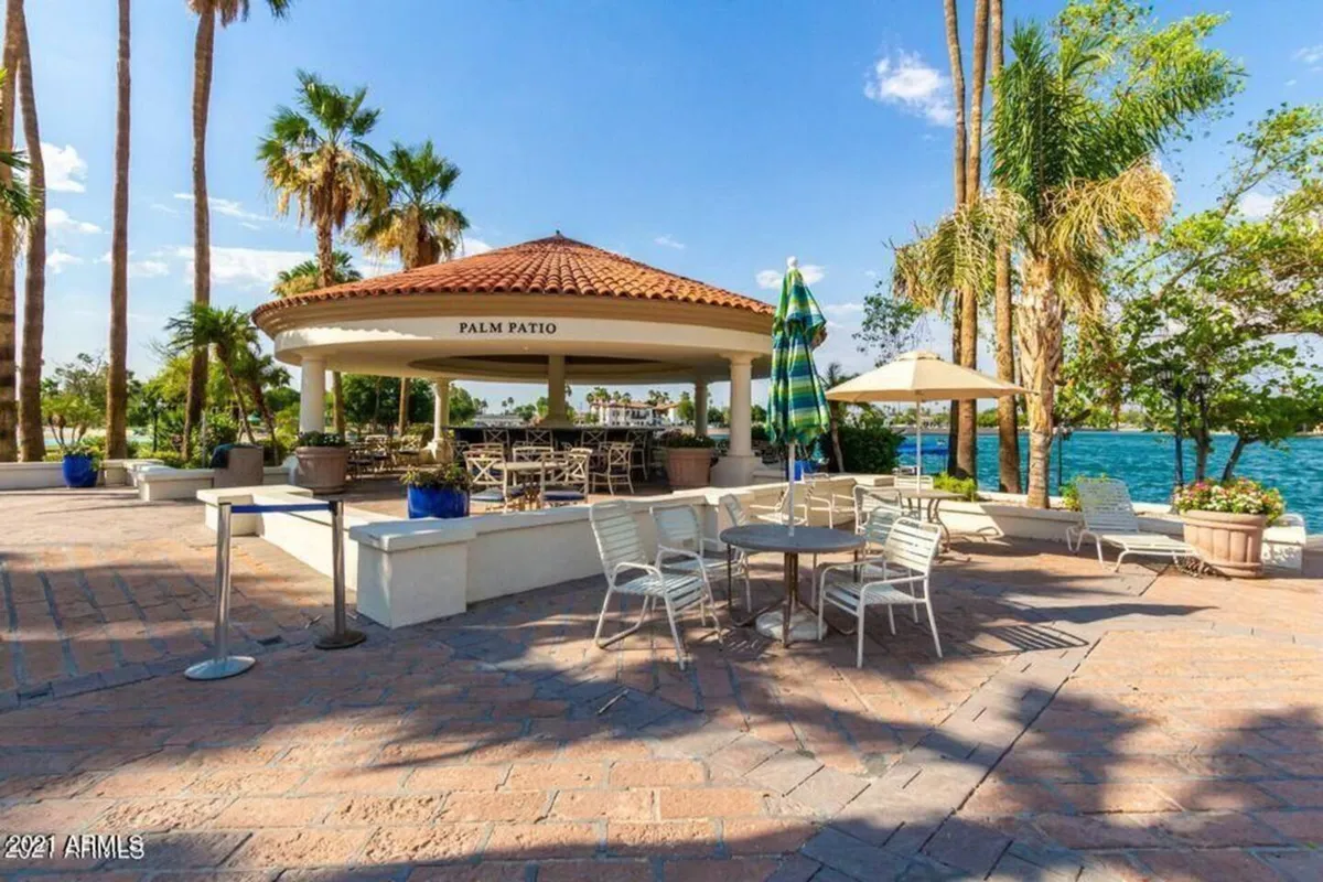 A relaxed outdoor seating area nestled under palm trees next to a waterfront gazebo labeled 'Palm Patio.' The area appears lively yet tranquil, ideal for socializing or taking a break from indoor gaming action.